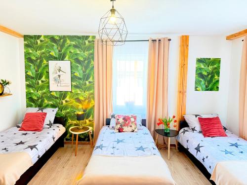 two beds in a room with a tropical wallpaper at Noclegi Świerzawa 43 in Świerzawa