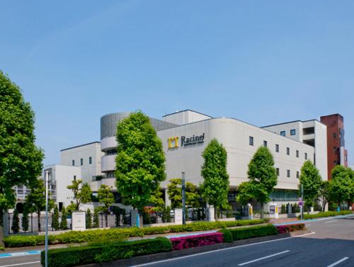 un grand bâtiment blanc avec des arbres et une rue dans l'établissement Racine Shinmaebashi, à Maebashi