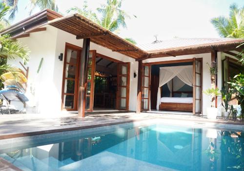 a villa with a swimming pool in front of a house at Marevka - Pool Villa with garden in General Luna