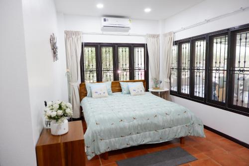 a bedroom with a bed in a room with windows at Pran Botanica Private Pool Villa in Ban Rom Pho
