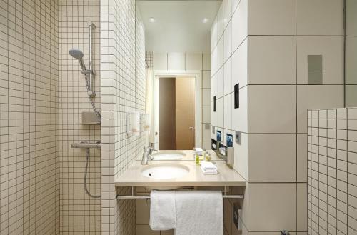 a white bathroom with a sink and a shower at Hilton Reykjavik Nordica in Reykjavík