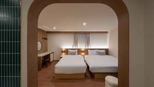 a hotel room with two beds and a mirror at Maison The Denbasta Hotel in Busan