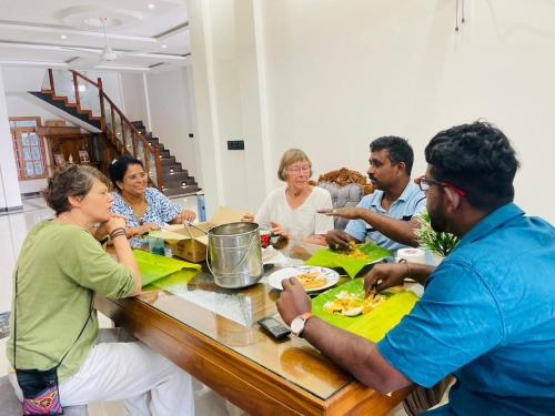 a group of people sitting around a table eating food at MTR Guesthouse in Jaffna
