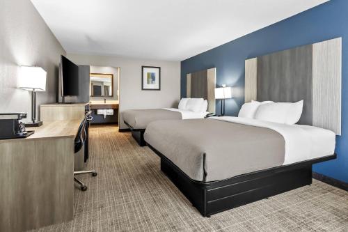 a hotel room with two beds and a desk at Quality Inn & Suites Florence Civic Center in Florence