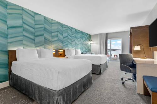 a hotel room with two beds and a desk at Cambria Hotel Ocean City - Bayfront in Ocean City