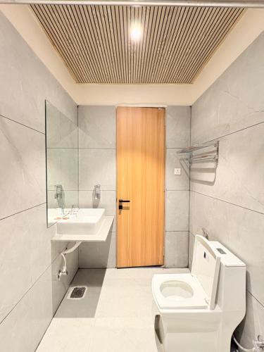 a bathroom with a toilet and a sink and a wooden door at Hotel Moti Mahal in Ambikāpur