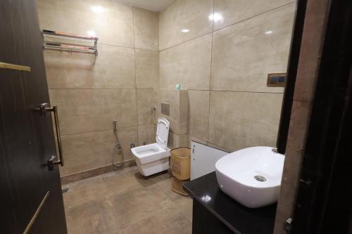 a bathroom with a white toilet and a sink at Hotel Carnival in Bāghpat