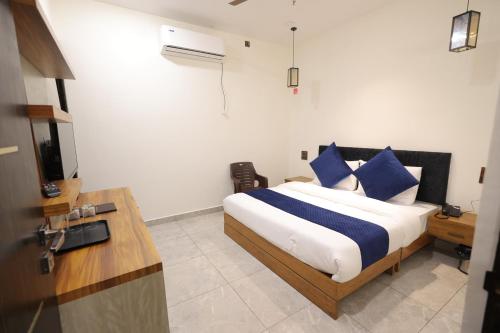 a bedroom with a bed with blue pillows and a television at Hotel Carnival in Bāghpat