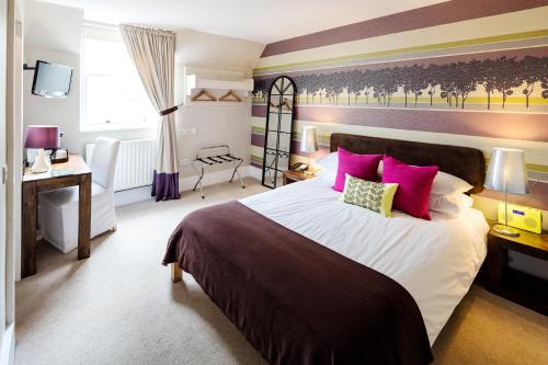 a bedroom with a large bed with pink pillows at The Victoria in London