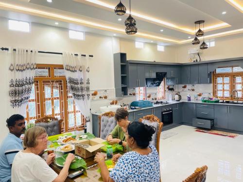 a group of people sitting around a table in a kitchen at MTR Guesthouse in Point Pedro