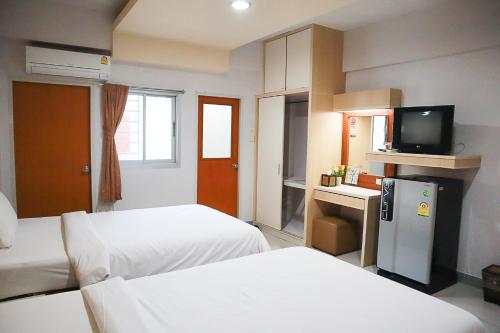 a hotel room with two beds and a television at 100House Hotel Korat in Ban Hua La Loeng