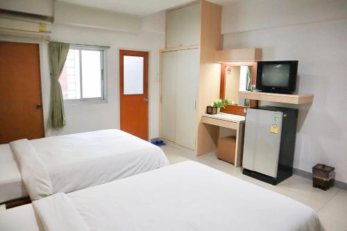 a hotel room with two beds and a television at 100House Hotel Korat in Ban Hua La Loeng