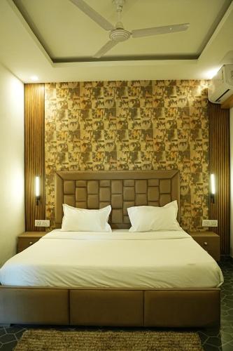 a bedroom with a large white bed with a brick wall at Sundown Resort in Noida