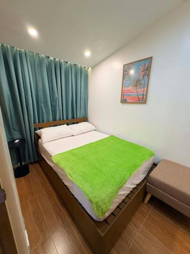 a bedroom with a bed with a green blanket on it at BMF Tropical Homestay in Calampanan