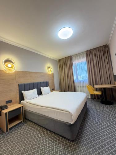 a hotel room with a large bed and a table at Golden Palace Hotel in Almaty