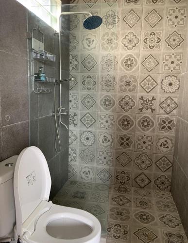 a bathroom with a toilet and a shower with tiles at De'Rein Beach House in Sanur