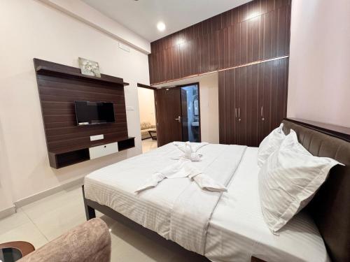 a bedroom with a bed with a tv on the wall at Radial Serviced Apartments in Chennai