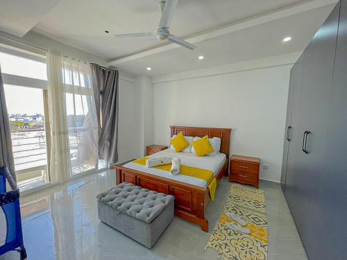 a bedroom with a bed and a chair and a window at Aqua seaside Apartments in Mombasa