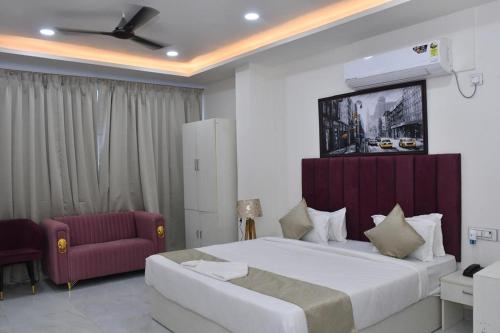 a bedroom with a large bed and a red couch at Bisaka Hotels in Patna