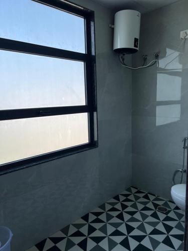a bathroom with a window and a black and white tiled floor at Bhavya Guest House in Rīngas