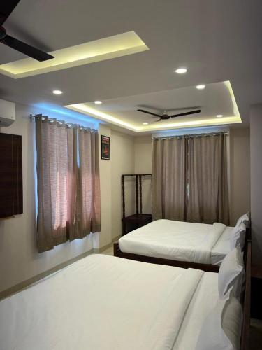 a bedroom with two beds and a ceiling at Bhavya Guest House in Rīngas