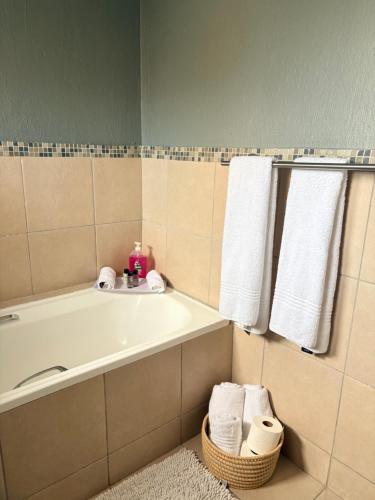 a bathroom with a tub and a sink and towels at Tranquil Arcade in Boschrand