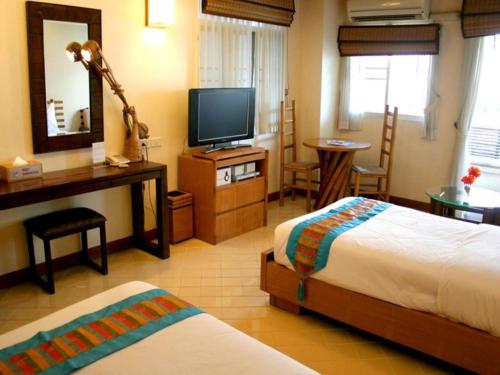 a hotel room with two beds and a television at Gerard Habitat Hotel in Chiang Mai