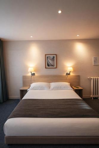 a large bed in a hotel room with two lamps at Hotel Cosmos in Paris