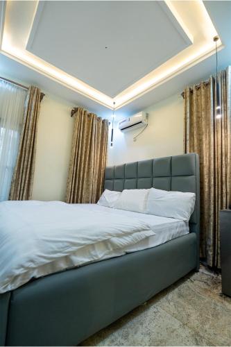 a large bed in a room with curtains and a ceiling at Sanctum Suites in Abuja