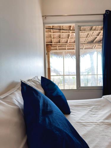 a bed with blue pillows in front of a window at Havana Beach Villa in Alleppey