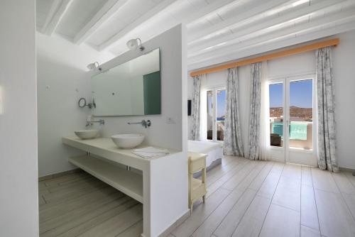 a white bathroom with a sink and a mirror at Arte & Mare Elia Luxury Suites and Villas in Elia Beach