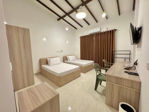 a bedroom with two beds and a desk and a television at The Dimora Residence in Kurunegala
