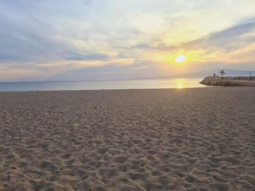 a sandy beach with the sun setting in the distance at Traditional mama house in Skala Sotiros