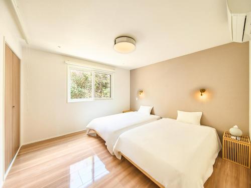 two beds in a bedroom with a window at HUG me Ocean awaji in Sumoto