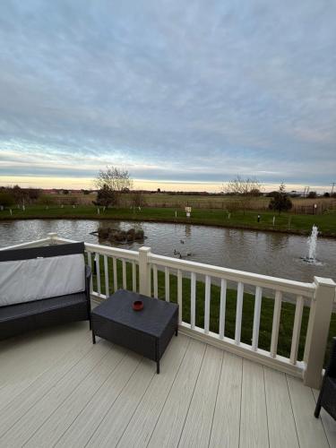 a deck with a bed and a couch and a view of a lake at Golden Palm, Meadow Lakes 8, Chapel St Leonards in Chapel Saint Leonards