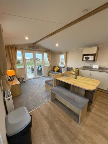 a caravan living room with a kitchen and a table at Golden Palm, Meadow Lakes 8, Chapel St Leonards in Chapel Saint Leonards
