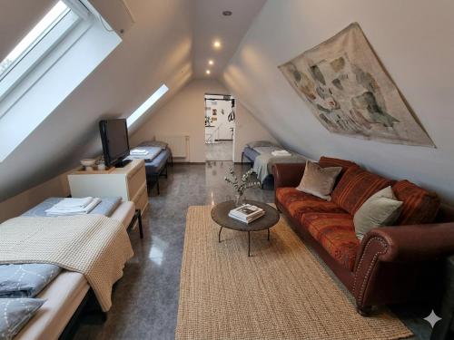 a attic living room with a couch and two beds at Drei-FreeParking Self-Check-In in Wolfpassing an der Hochleithen