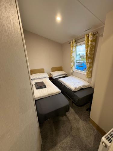 a small room with two beds and a window at Golden Palm, Meadow Lakes 8, Chapel St Leonards in Chapel Saint Leonards