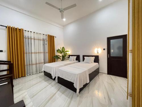 a bedroom with two beds and a flat screen tv at Yala Cherish Inn & Safari in Tissamaharama