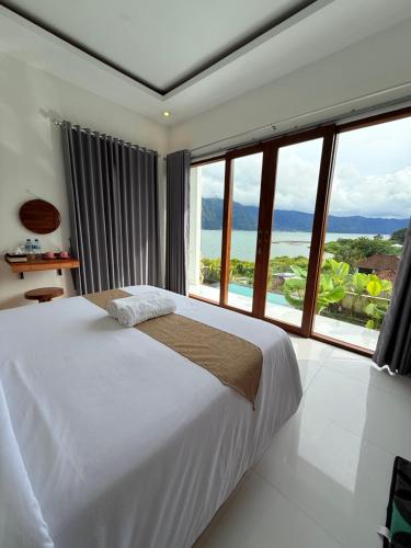 a bedroom with a large bed and large windows at Kayana Lake View in Kubupenlokan
