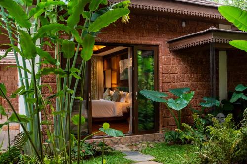 a house with a glass door with a bed in it at The Leela Coorg Forest Sanctuary in Madikeri
