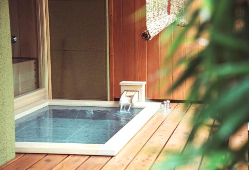 a swimming pool on a house with a wooden floor at Yamatoya Besso in Matsuyama