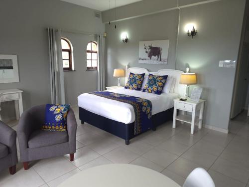 a bedroom with a king sized bed and a chair at Fairway Guest Lodge in Margate