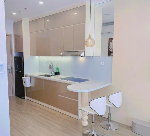 a kitchen with a white counter and two stools at Homestay Ocean Park Building P3 in Gia Lâm Pho