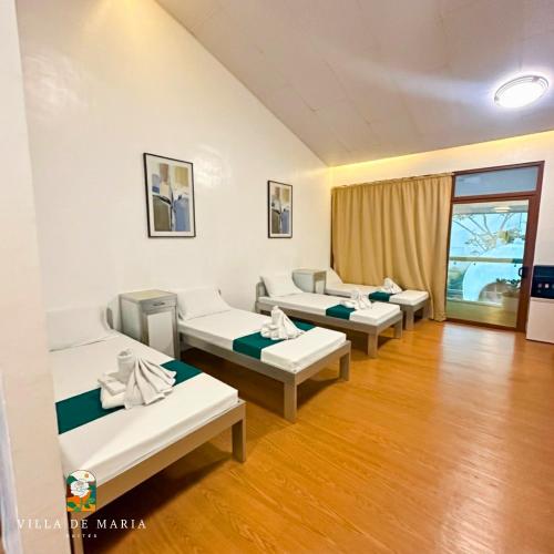 a hospital room with three beds and a window at Villa de Maria Suites in Binungan