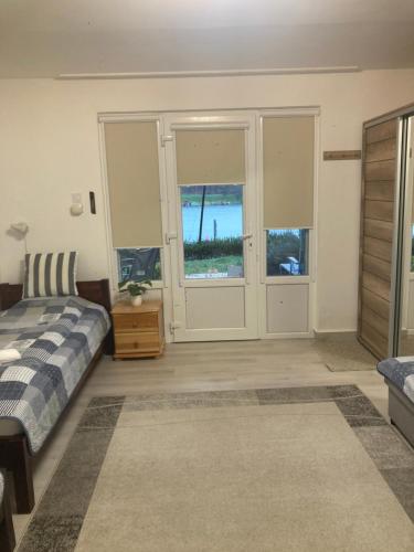 a bedroom with a bed and a door with windows at Oázis Apartman in Orfű