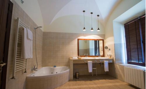 a bathroom with a tub and a sink and a mirror at Hospedium Hotel Cortijo Santa Cruz in Villanueva de la Serena