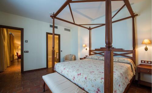 a bedroom with a canopy bed and a white bench at Hospedium Hotel Cortijo Santa Cruz in Villanueva de la Serena