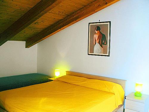 a bedroom with a yellow bed with a picture on the wall at Gelsomino home in Furore