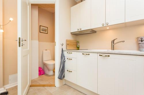 a kitchen with white cabinets and a toilet at Lossiplatsi Apartment in Haapsalu